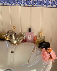 a bathroom sink with soap, perfume and flowers on it