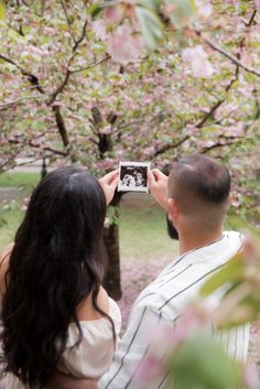 a man and woman are taking pictures in the park