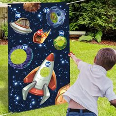 a young boy is playing with a rocket ship and space shuttle game in the yard