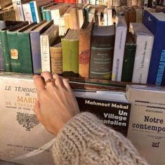 a person standing in front of a bookshelf filled with many different colored books