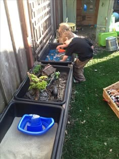 a little boy playing with some plants in the back yard