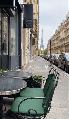 two chairs and a table sitting on the sidewalk in front of a building with an eiffel tower in the background