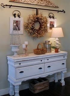 a white dresser sitting under a chandelier in a living room next to a lamp