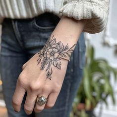 a woman's hand with a flower tattoo on her left wrist and the other arm