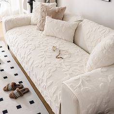 a white couch with pillows and slippers on it