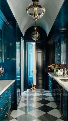 a blue and black kitchen with checkered flooring, gold accents and chandelier