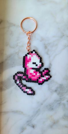 a pink and black pixel keychain sitting on top of a marble counter