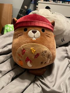 a stuffed animal wearing a red hat on top of a bed