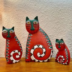 three ceramic cats sitting on top of a wooden table