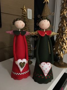 two small dolls are standing next to each other on a shelf in front of a christmas tree