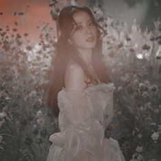 a woman in a dress standing in front of flowers