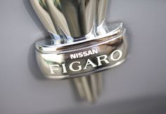 a close up of a metal object with the word nissan figaro written on it