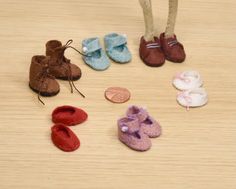 there are several small baby shoes next to a doll's feet on the floor