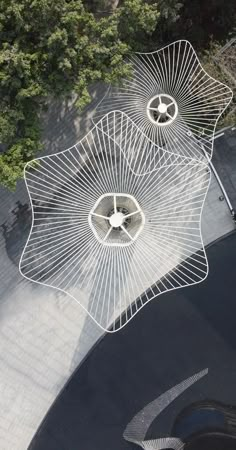 an aerial view of two umbrellas on the ground in front of some trees and bushes