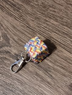 a multicolored keychain with a metal hook on a wooden table top