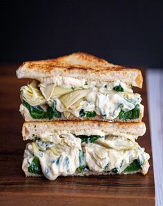 two sandwiches stacked on top of each other with cheese and spinach in the middle