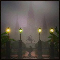 a person riding a horse in the rain at night with street lights on and behind them