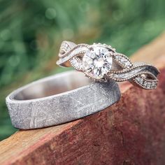 a wedding ring with an intricate design on it sitting on top of a piece of wood