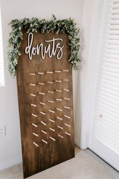 a wooden sign with the word donuts on it next to a white door and window