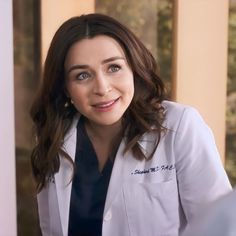 a woman in a white lab coat smiles at the camera