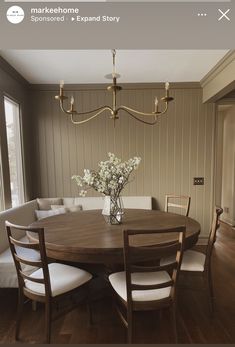 a dining room table and chairs with flowers in a vase on the center, next to a couch