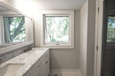 a bathroom with two sinks and a large window in the corner on the far wall