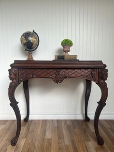 a wooden table with a globe on top of it next to a book case and plant