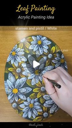 a person is painting a flower design on a plate with white paint and black marker