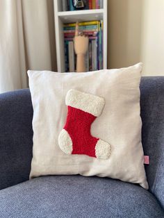 a white pillow with a red stocking on it sitting on top of a blue couch