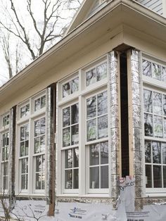 a house is under construction with windows and siding on the front porch, along with some trees