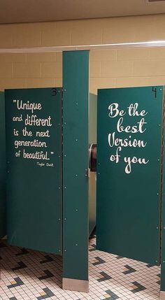 three green stalls with writing on them in a public bathroom stall, one is open and the other has closed doors