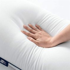 a woman's hand is on the back of a pillow that has been folded over