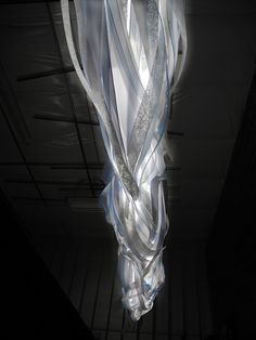 an artistic light hanging from the ceiling in a dark room with no people around it