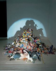 the shadow of a man is cast over a pile of garbage