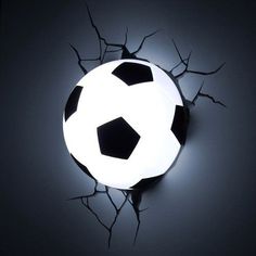 a black and white soccer ball in the middle of a cracked wall with light coming through it