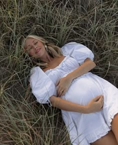 a pregnant woman is laying in the grass