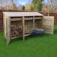 a wheelbarrow next to a shed filled with firewood in the grass outside