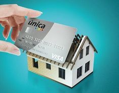 a person holding a credit card in front of a small house with the word finta on it