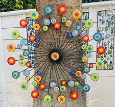 a tree with colorful circles on it next to a fence