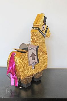 a golden llama with a pink ribbon on it's neck sitting on a black table