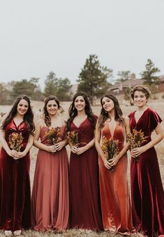 a group of women standing next to each other in long red dresses with flowers on them