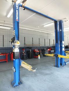 the inside of a garage with two lifts on each side and several other tools in the background