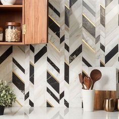 a kitchen counter with wooden utensils and white marble tiles on the backsplash