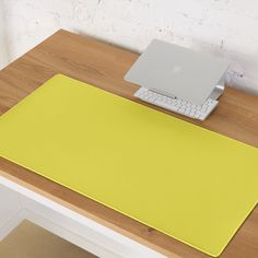 an apple laptop computer sitting on top of a wooden desk next to a yellow mouse pad