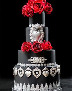 a three tiered cake with red roses on top and silver decorations around the edges