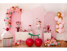 a pink and gold birthday party with balloons, cupcakes, cake and decorations