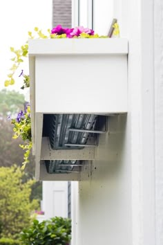 an open window on the side of a building with flowers hanging from it's windowsill