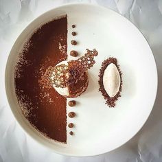 a white plate topped with two desserts on top of each other next to a spoon