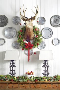 a deer head mounted to the side of a wall decorated with christmas wreaths and plates