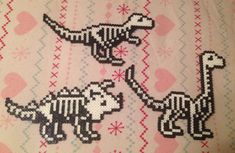 two cross stitch dinosaurs on a pink and white background